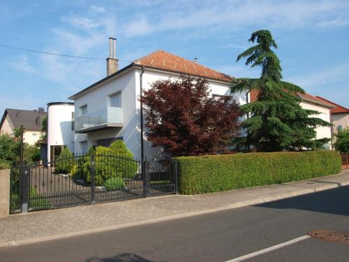 a white house with a fence and a tree at Studio apartman Rest Nest in Čakovec