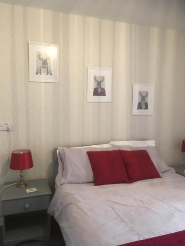 ein Schlafzimmer mit einem Bett und drei Bildern an der Wand in der Unterkunft Lewinsdale Lodge in Weston-super-Mare
