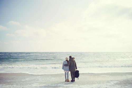 two people standing on the beach looking at the ocean at Strandhotel Zoomers in Castricum