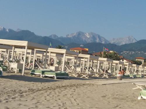 a row of lounge chairs and tables on a beach at Appartamento Versilia lungomare in Marina di Pietrasanta
