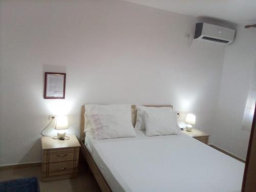 ein Schlafzimmer mit einem weißen Bett und zwei Nachttischen in der Unterkunft Sazani's Place in Fier