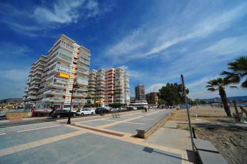 una calle de la ciudad con edificios altos y palmeras en Apartamentos Estoril I - II Orangecosta, en Benicàssim