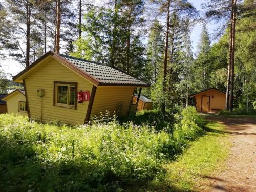 a small yellow cabin in the middle of a forest at Lohirannan lomakylä in Sukeva