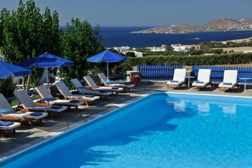 einen Pool mit Stühlen und Sonnenschirmen sowie das Meer in der Unterkunft Fragoulis Village in Parasporos