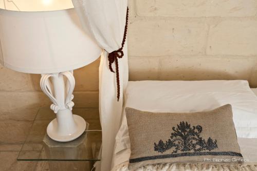 a lamp and a pillow next to a bed at Palazzo Dei Dondoli in Lecce
