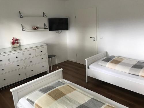 RottorfにあるFerienwohnung Forstwegのベッドルーム1室(ベッド2台、ドレッサー、テレビ付)