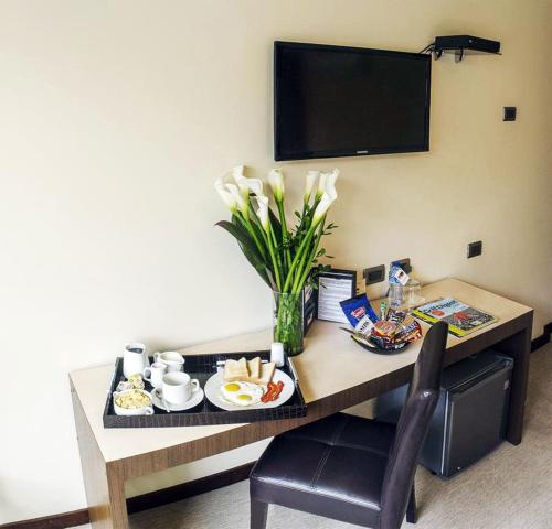 einen Tisch mit einem Teller Essen und einer Vase Blumen in der Unterkunft SM Hotel in Lima