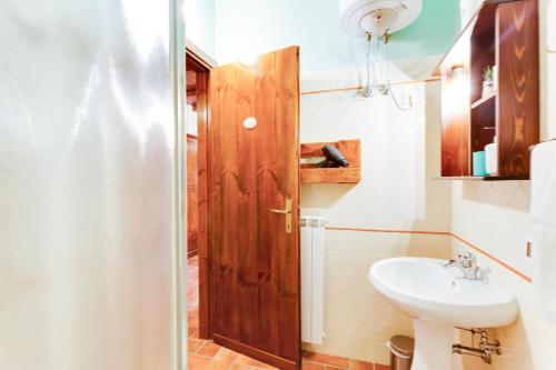ein Badezimmer mit einem Waschbecken und einer Holztür in der Unterkunft Agriturismo Casale Sasso in Cerveteri