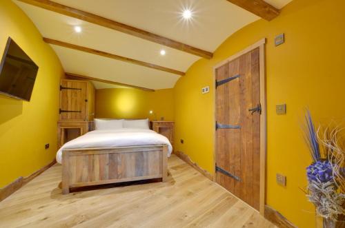 a bedroom with yellow walls and a bed and a door at Oastbrook Vineyard in Bodiam