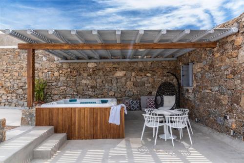 a patio with a hot tub and a table and chairs at Etesians Suites & Villas in Super Paradise Beach