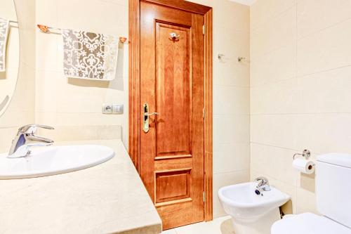 baño con lavabo y puerta de madera en Apartamento en Playa la Arena, en Puerto de Santiago