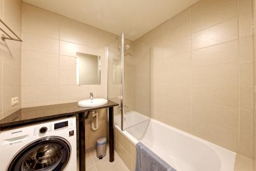 een badkamer met een wasmachine en een wastafel bij Aan de duinbossen in De Haan