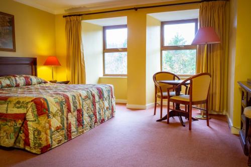 a bedroom with a bed and a table and chairs at Lynhams Hotel in Laragh