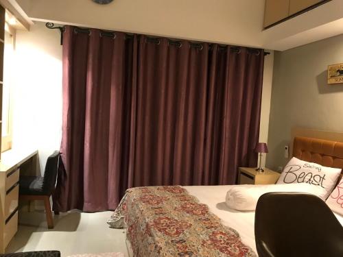 een slaapkamer met een bed met paarse gordijnen bij Ruang Bravia Bogor Icon Hotel in Bogor