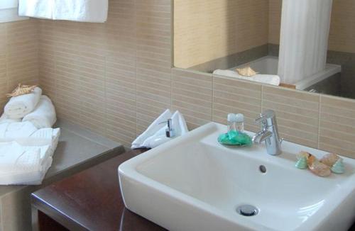 a bathroom with a sink and a mirror and towels at Apolis Beachscape Hotel in Amoopi