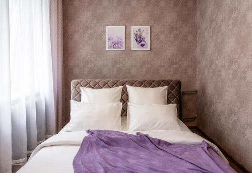 ein Bett in einem Schlafzimmer mit zwei Bildern an der Wand in der Unterkunft PaulMarie Apartments on Gogolya 39 in Bobruisk