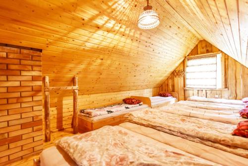 Kempings Videnieki في Liepene: غرفة نوم بثلاث اسرة في كابينة خشبية