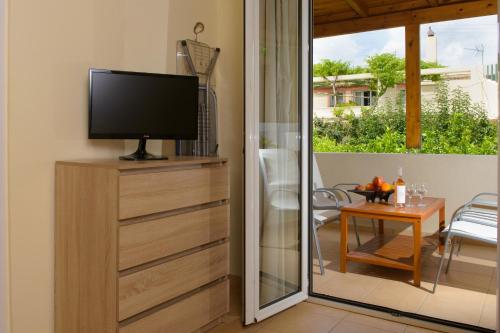 TV en un tocador con puerta corredera de cristal en Ammoudara Beach Hotel Apartments en Ágios Nikólaos