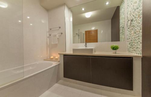 uma casa de banho com uma banheira, um lavatório e um espelho. em B27 - LuzBay 2 Bed Apartment na Praia da Luz