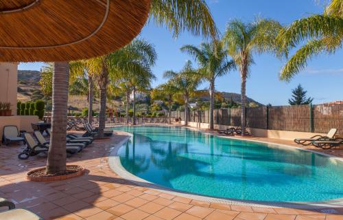 a swimming pool with palm trees in a resort at B27 - LuzBay 2 Bed Apartment in Luz
