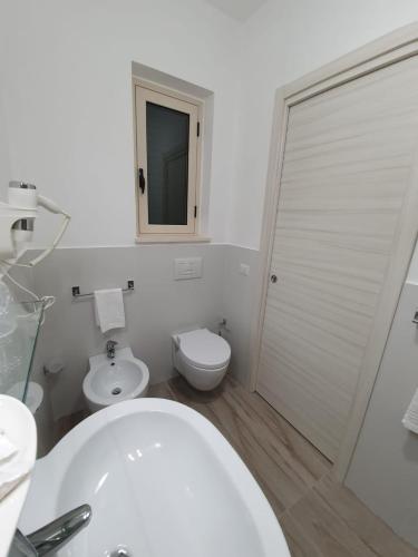 a white bathroom with a toilet and a sink at Oikia Rooms in Parghelia