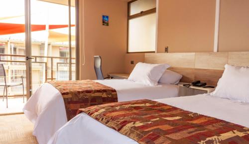 a hotel room with two beds and a balcony at Hotel Vento in Copiapó