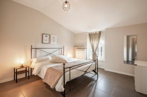 una camera da letto con un letto con lenzuola bianche e una lampada di L'Angelica Holiday Home a Desenzano del Garda