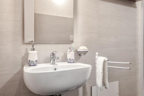 a white bathroom with a sink and a mirror at Giardini Acantus in Rosolini