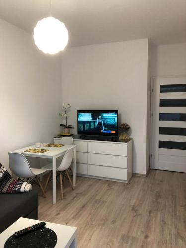 ワルシャワにあるApartamenty Metro Słodowiec, free parking Żeromskiego 1 CMKP- 5 minのリビングルーム(テレビ、テーブル、椅子付)