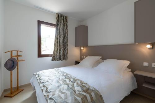 a bedroom with a white bed and a window at Domaine A Marella in LʼÎle-Rousse