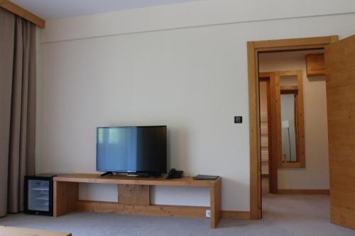 a living room with a television on a wooden table at Monte Cervo Bio Hotel & Spa in Covasna