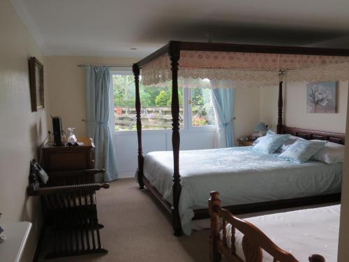 ein Schlafzimmer mit einem Himmelbett und einem Fenster in der Unterkunft Cuil Na Sithe in Fort William