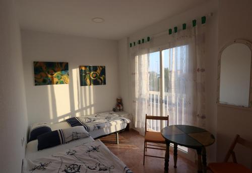 a bedroom with two beds and a table and a window at Casa Antonio in Águilas