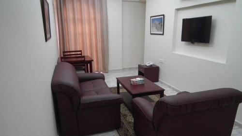 a living room with two chairs and a tv at Al Ferdous Hotel Apartments in Muscat