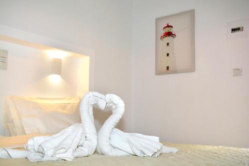 a towel swan sitting on a bed with a lighthouse at Golden Star Praxitelous in Agia Marina Aegina