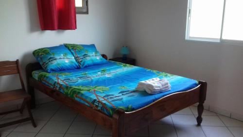 um quarto com uma cama com um edredão azul em T3 Bel Enclos SCHOELCHER Kybo Karaib Location Vue mer Calme em Schœlcher