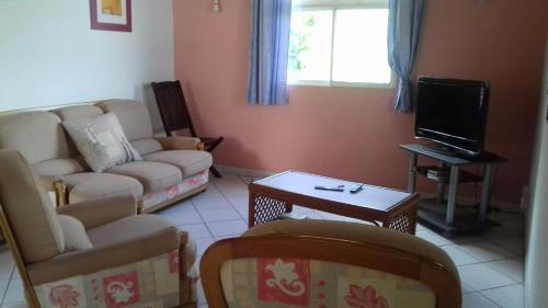 uma sala de estar com um sofá e uma televisão em T3 Bel Enclos SCHOELCHER Kybo Karaib Location Vue mer Calme em Schœlcher