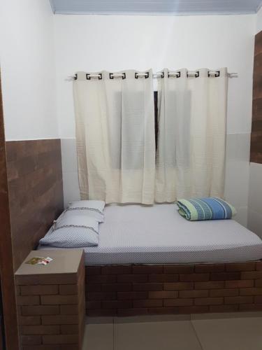 a bed in a brick room with a window at Pouso in Pirenópolis