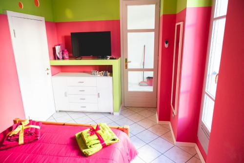 - une chambre rose et verte avec un lit et une télévision dans l'établissement A casa dalla Fra, à Castelfranco Emilia