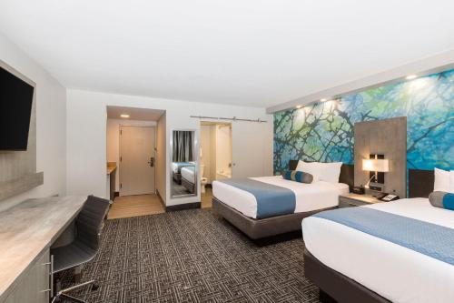 a hotel room with two beds and a flat screen tv at Wingate by Wyndham Goodlettsville in Goodlettsville