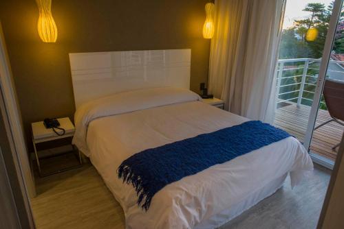 a bedroom with a bed with a blue blanket on it at 2122 Hotel Art Design in Punta del Este