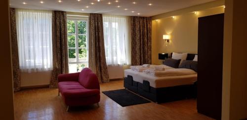 a bedroom with a bed and a chair and window at Hotel Villa Lalee in Dresden