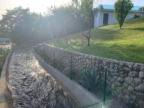 a stone retaining wall next to a field and trees at Ferienhaus in Široki Brijeg