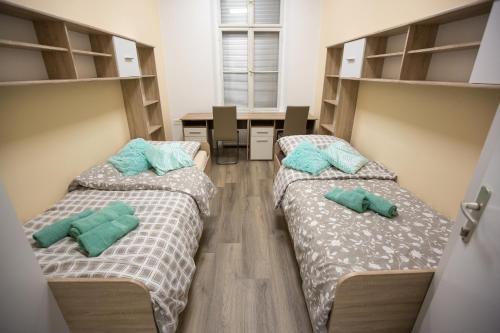 two beds in a dorm room with desks and a desk at MINIDORM ROOMS IN HEART OF CITY CENTER in Maribor