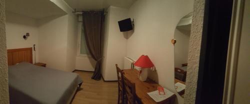 a bedroom with a bed and a table with a red lamp at HOTEL DE FRANCE in Maubourguet