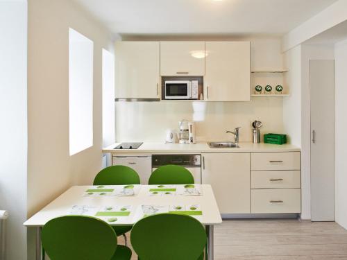 a kitchen with green chairs and a white table at Design Studios SVI-MI in Zagreb