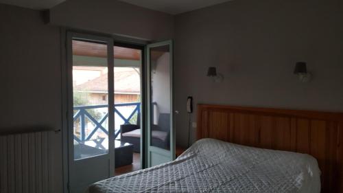 a bedroom with a bed and a door to a balcony at HOTEL DE FRANCE in Maubourguet