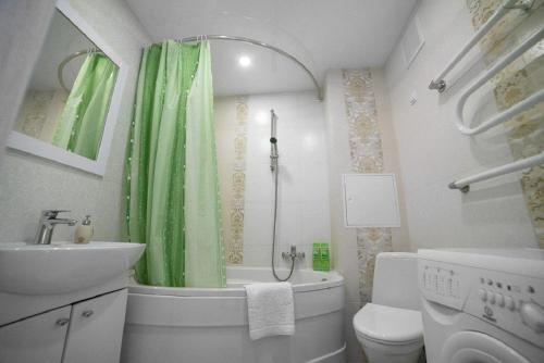 a bathroom with a sink toilet and a green shower curtain at PaulMarie Apartments on Kozlova in Soligorsk