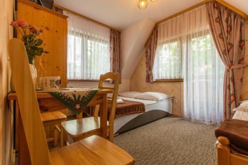 ザコパネにあるWilla Lassakówkaのベッド、デスク、窓が備わる小さな客室です。