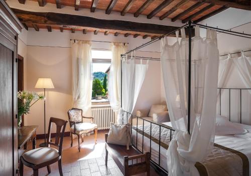 um quarto com uma cama de dossel e uma cadeira em B&B L'orto Delle Terme em Bagno Vignoni